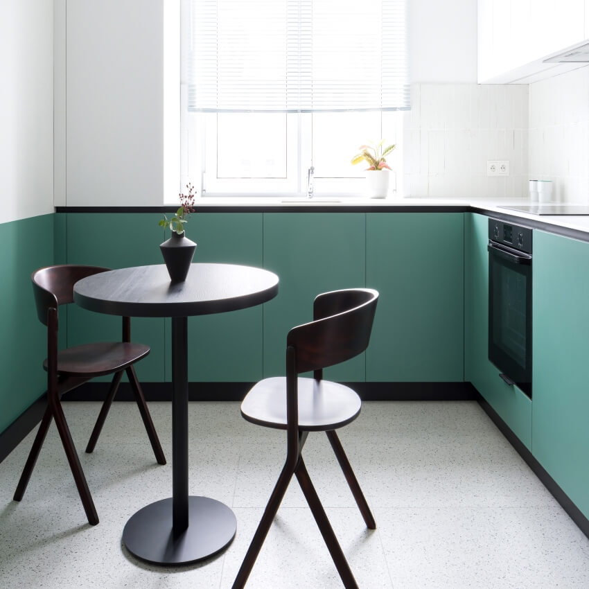 Small kitchen with terrazzo floor, black dining table, and white and green cabinets