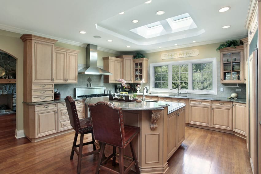 Spacious kitchen with wood floor, center island, backsplash, skylight, windows, and pickled oak cabinets