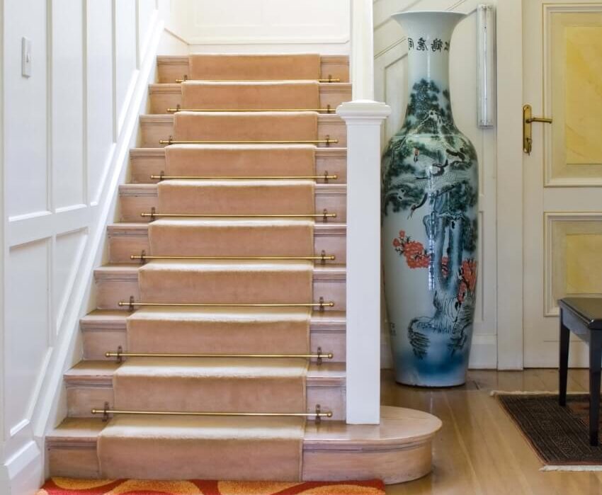 Stairway in modern home with wool carpet runner, and ancient Chinese art vase on the side