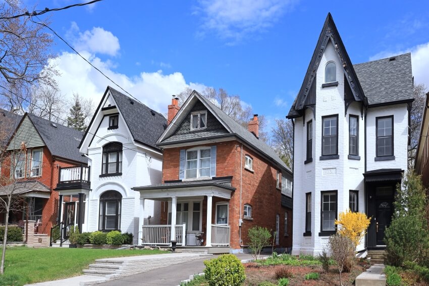 Street with row of narrow old brick detached houses with gables and different exterior paints