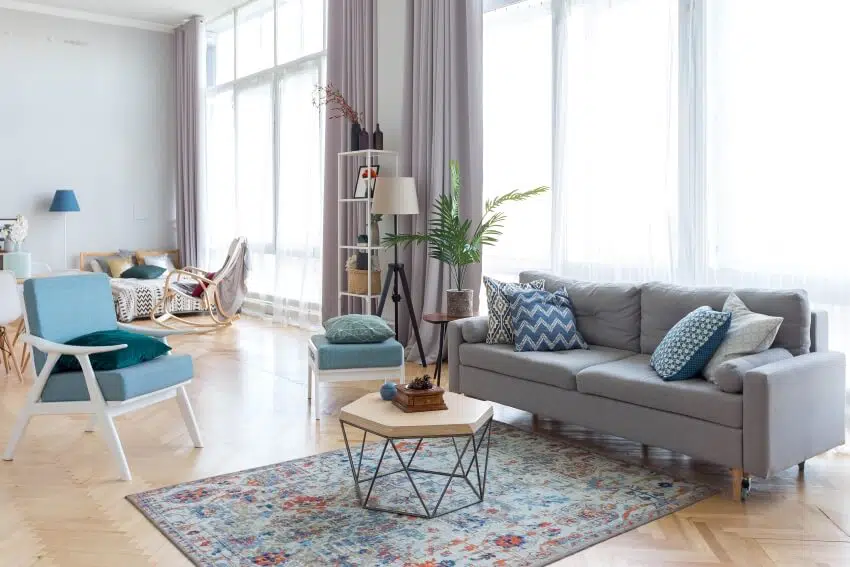 Studio apartment in blue and grey tone with coffee table, sofa, parquet floor, and panoramic windows