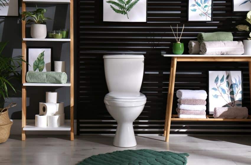 Stylish bathroom with artwork above toilet tank and wood shelves and table with bathroom essentials