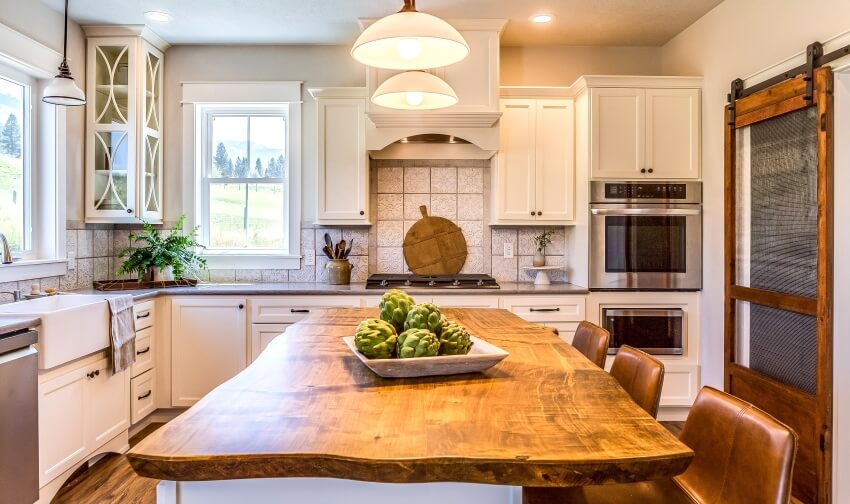 Tile backsplash, natural wood countertop on island with dome pendant lights above in a country kitchen