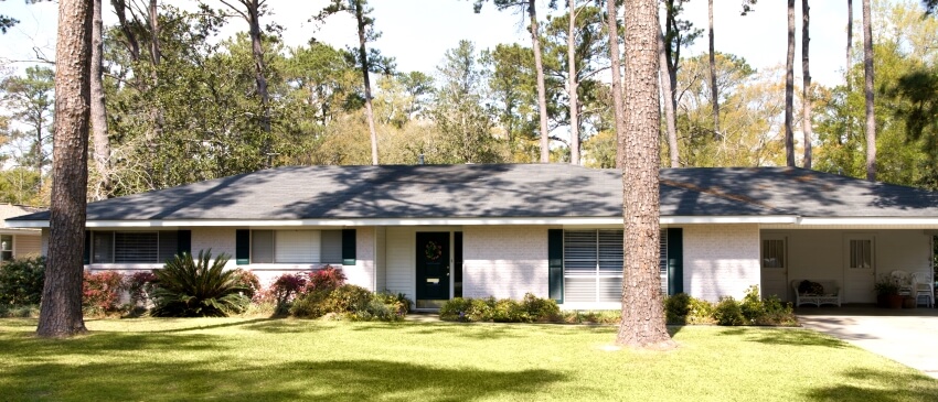 Typical American home with white brick exterior, driveway, and lawn with trees