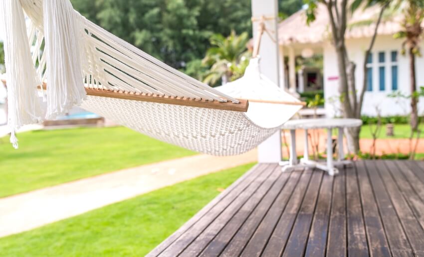 White hammock with a wooden spreader bar in a deck