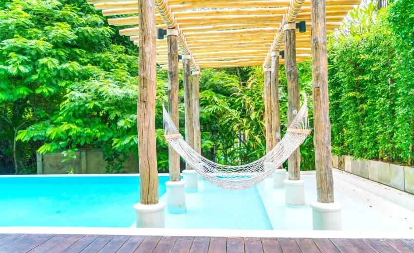White hammocks between wood posts in luxury swimming pool