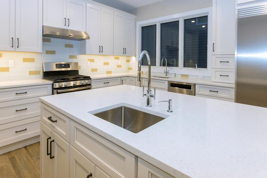 White kitchen with glass tile backsplash, under cabinet lighting, and acrylic countertops