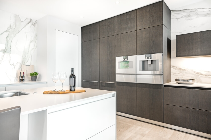 White kitchen with marble backsplash, matte laminate cabinets, and stainless steel appliances