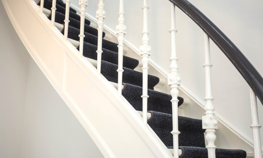 Wooden stairs with white railings and grey carpet runner