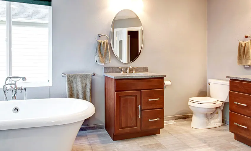 Room with freestanding tub, brown cabinets and toilet