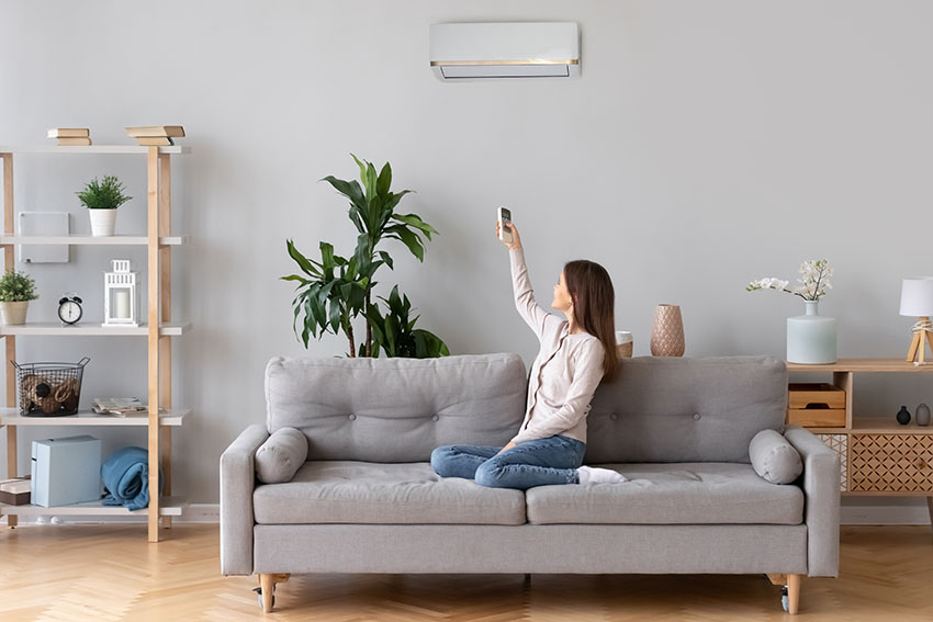 Woman in sofa switching air conditioner
