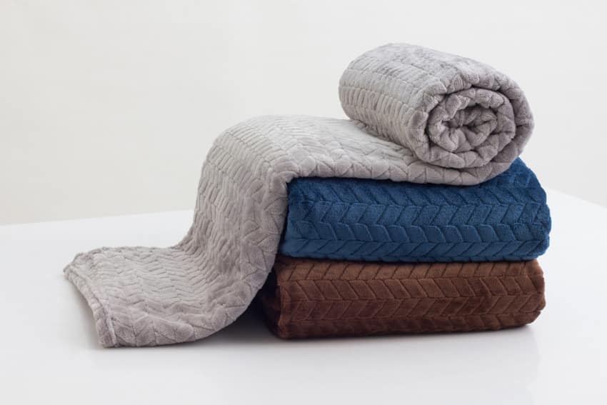 A stack of gray, blue, and brown comforters