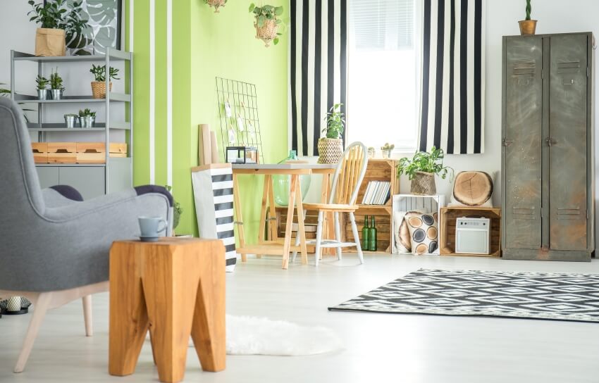 Scandinavian themed craft room with yellow green accent wall, wood furniture, plants, and a carpet