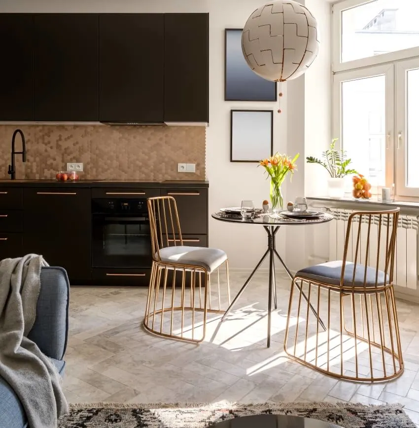 Apartment with two seater table, stylish chairs, black kitchen, and herringbone pattern floor