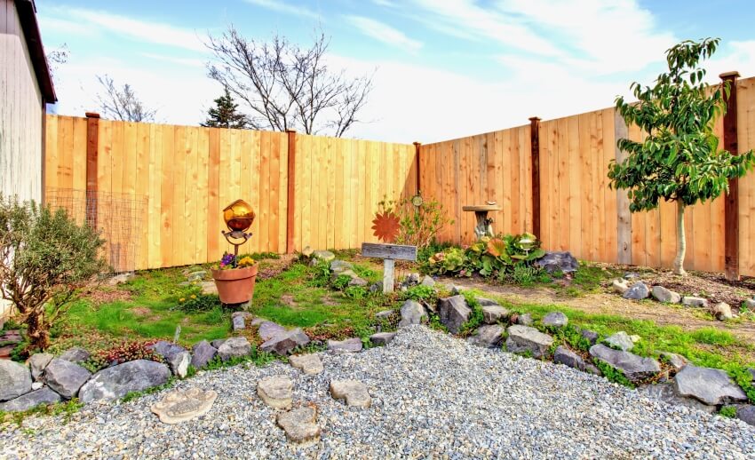 Backyard landscape design with stones and wood fence