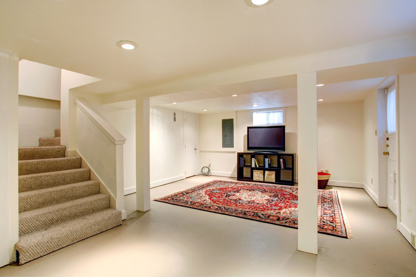 Basement area with rug, painted floor, television, and ceiling lights