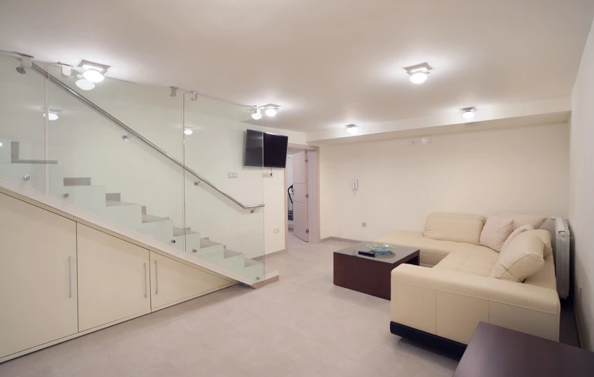 Room in the basement with stairs, sectional sofa, staircase with glass railing