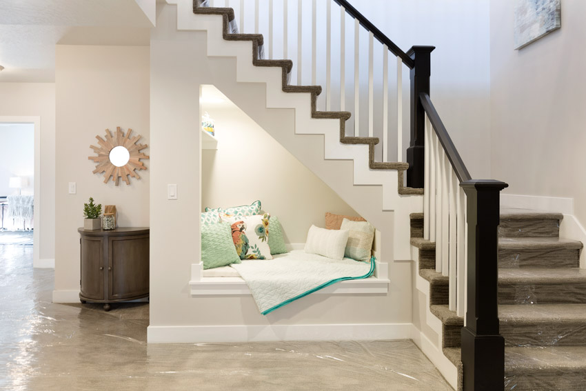 Room with cushioned nook, wood table, mirror and staircase