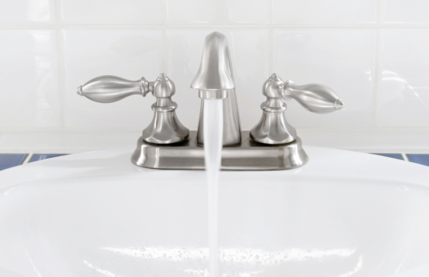 Brushed nickel bathroom faucet with controls positioned on top of a sink