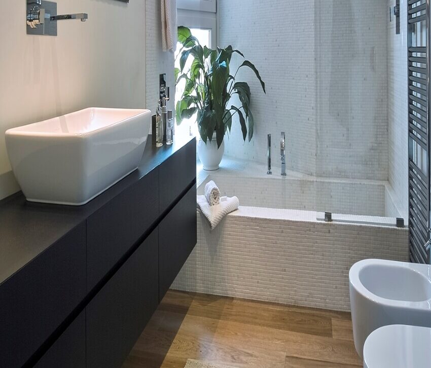 Bathroom interior with wooden floor, black floating countertop, and a mirror with track lighting