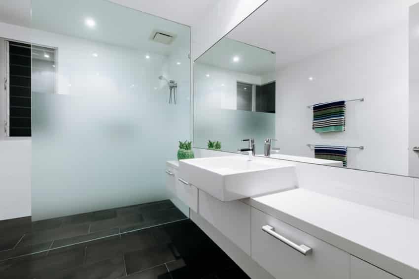 Bathroom with floating vanity, white sink, mirror, glass divider, and shower area
