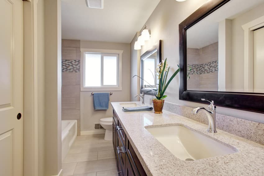 Bathroom with granite surfaces, mirror, vanity, sink, faucet, toilet, and window