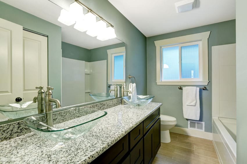 Bathroom with green wall, granite countertop, mirror, wood floor, toilet, and window