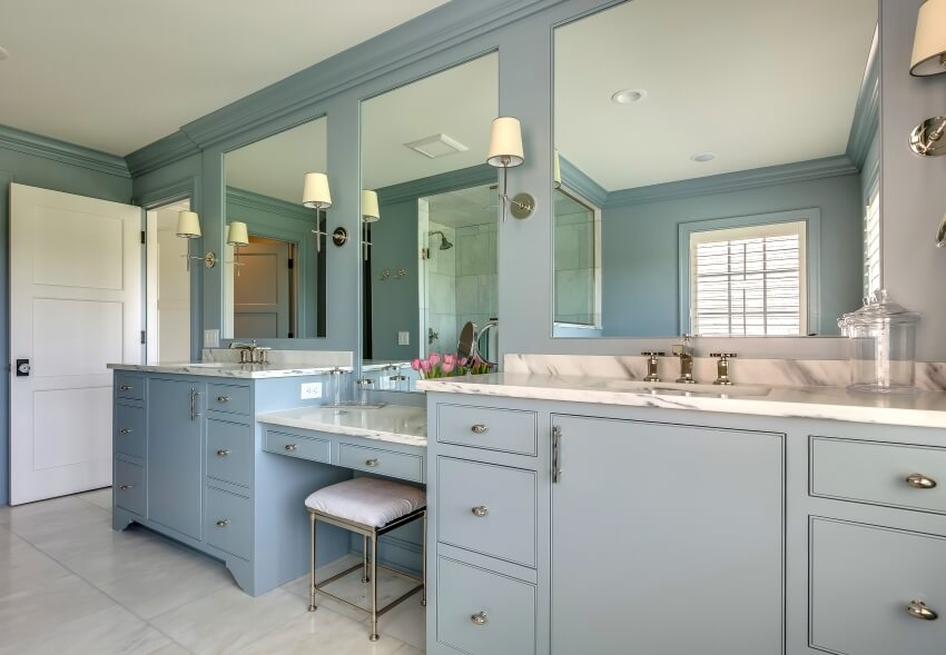 Bathroom with long light blue vanity with marble countertops and wall lamps