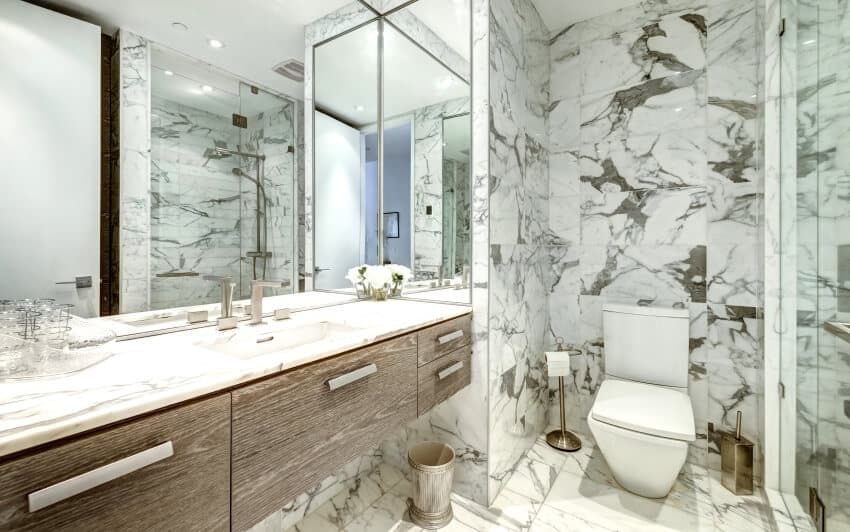 Bathroom with marble tile wall and floor, large mirror, and marble countertop