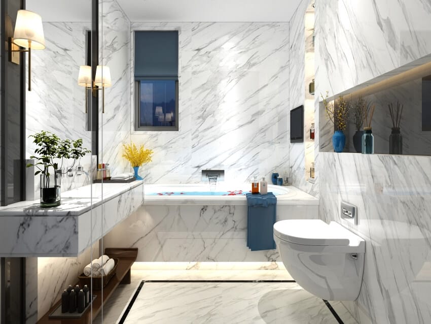 Bathroom with marble walls and floor, recessed shelf, sconce lights, and floating marble countertop