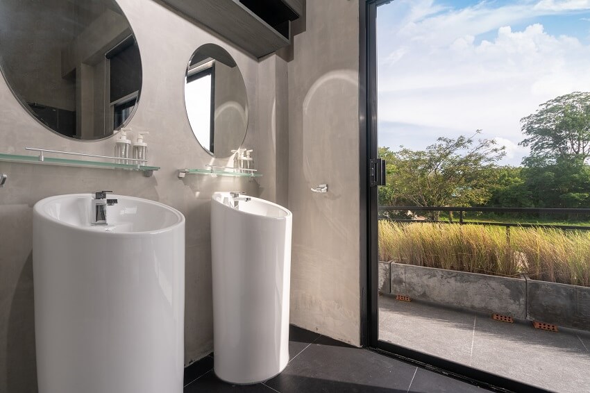 A bathroom with round vanity sink and an outside view of grass and trees