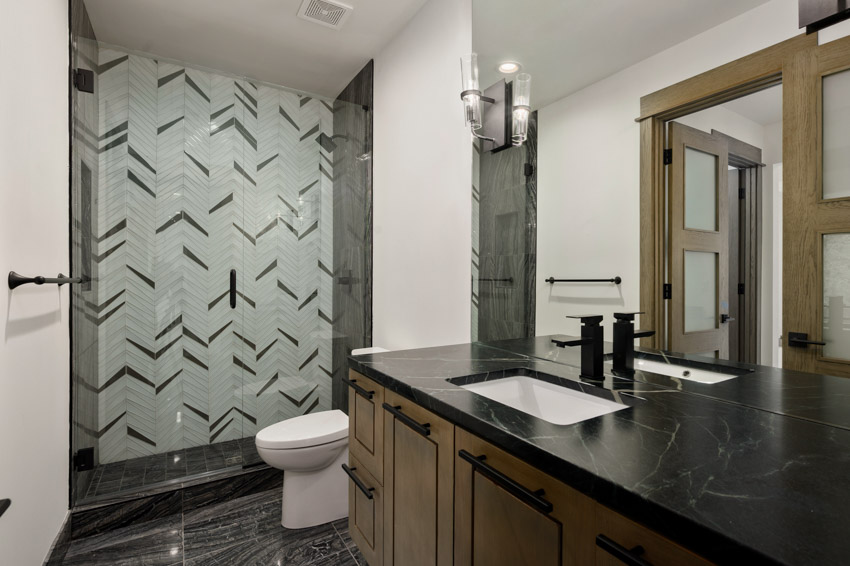 Bathroom with soapstone countertop, mirror, faucet, sink, toilet, and shower area
