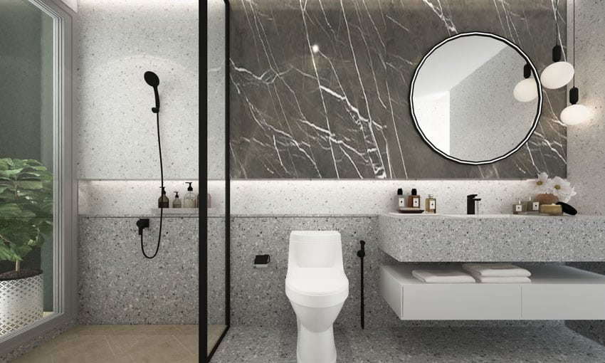 Bathroom with terrazzo shower wall, mirror, vanity area, and toilet
