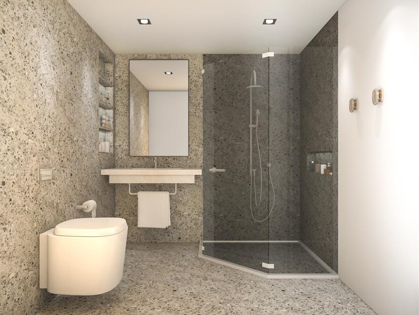 Bathroom with terrazzo walls, floors, toilet, mirror, and vanity area