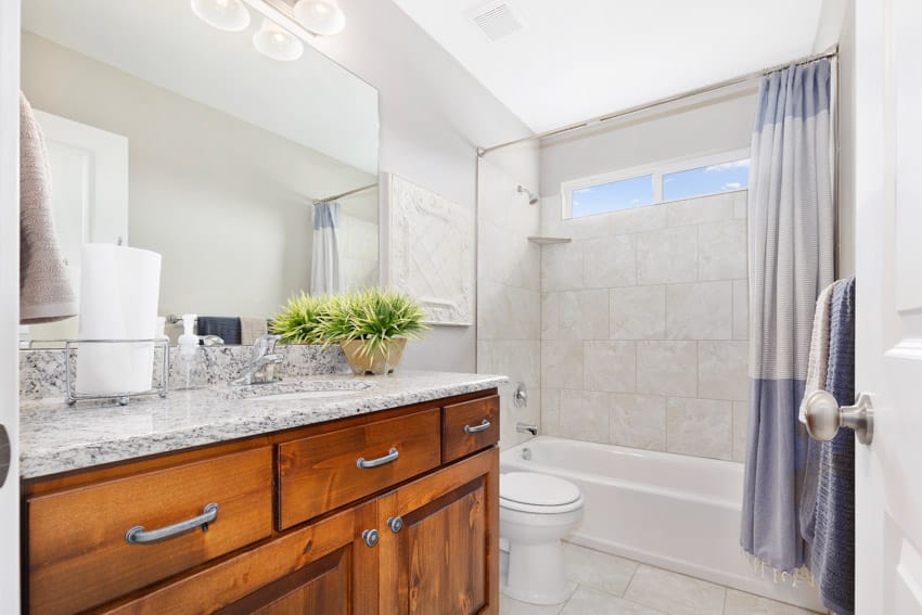 Bathroom with alcove tub, toilet, white walls and windows