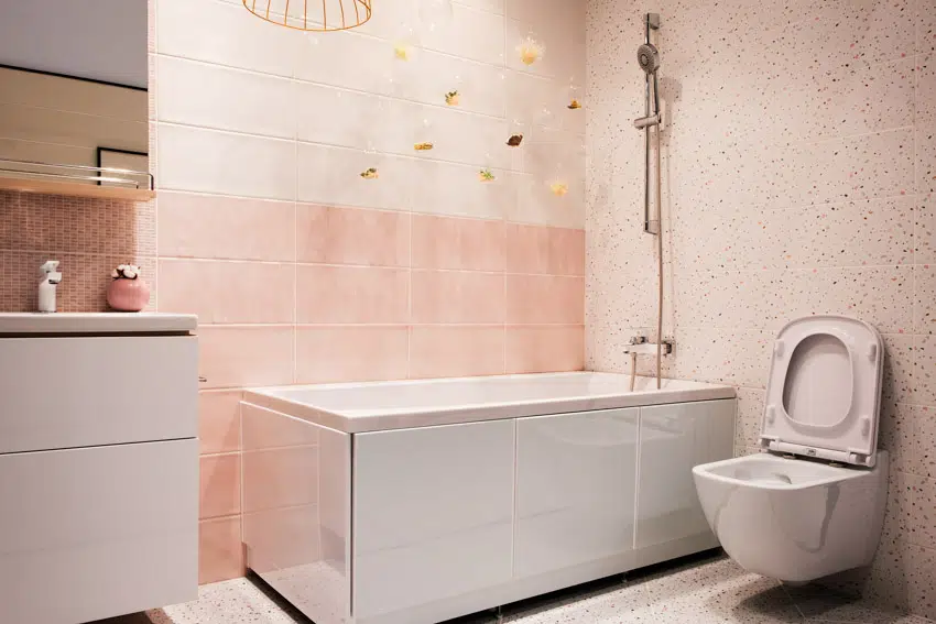 Bathroom with tub, terrazzo shower wall, toilet, and showerhead