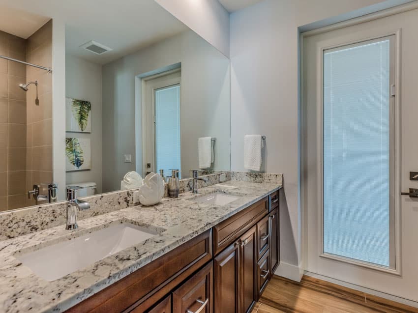 Bathroom with vanity, mirror, granite countertop, glass door, and wood cabinets