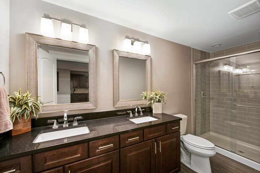 Bathroom with vanity mirror, soapstone countertop, wood cabinets, toilet, and shower area