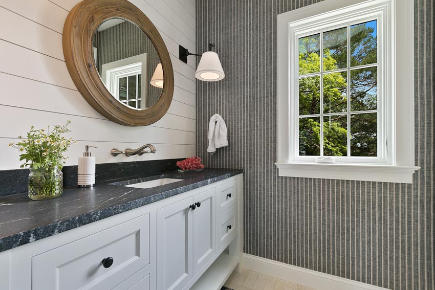 Bathroom with wood siding backsplash, soapstone countertops, white cabinets, and windows