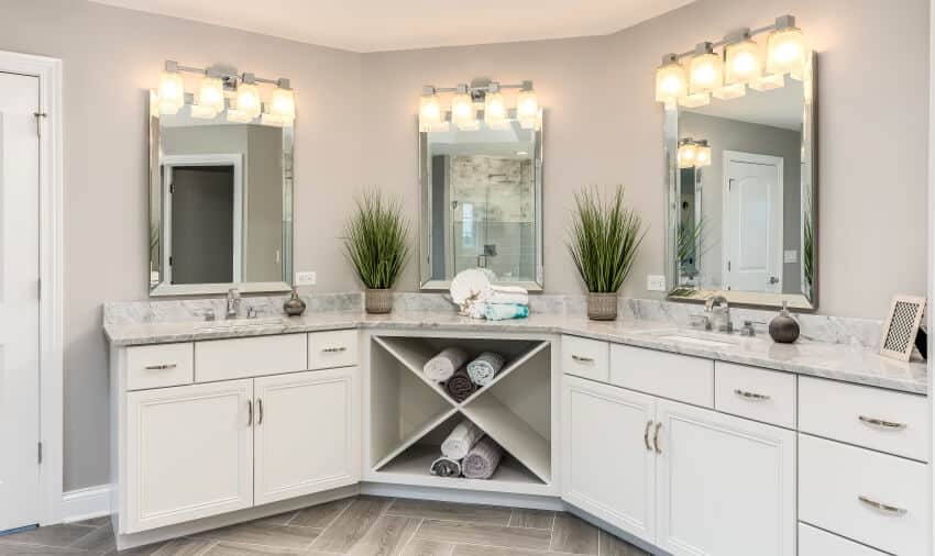 Beautiful cornered vanity area in bathroom with wall track lights and marble countertops