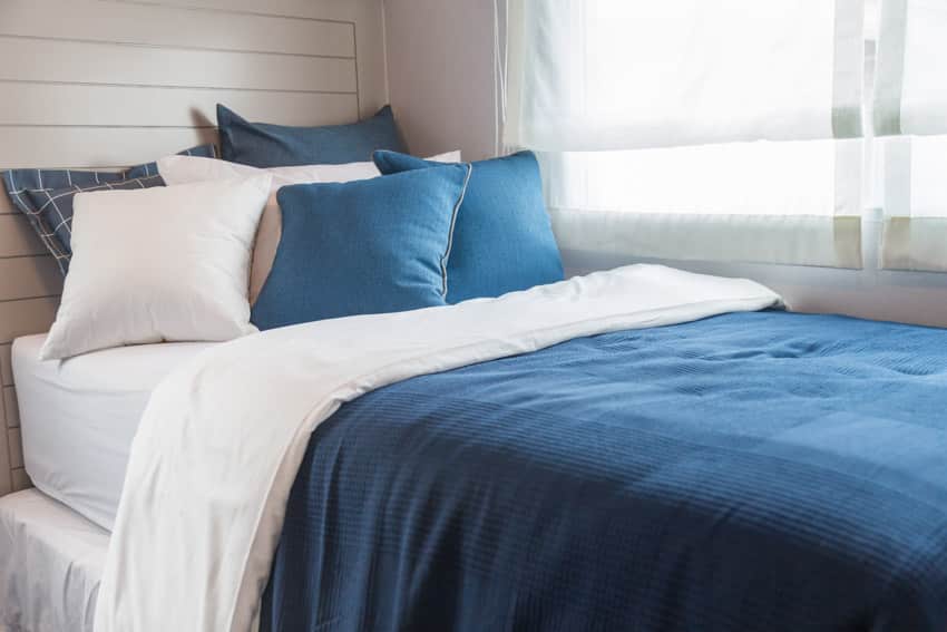 Bedroom with white mattress and blue comforter