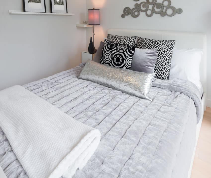 Bedroom with channel stitch comforter, pillows, nightstand, and lamp