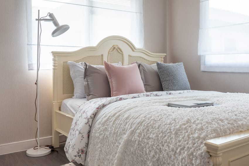 Bedroom with comforter, pillows, mattress, windows, and floor lamp