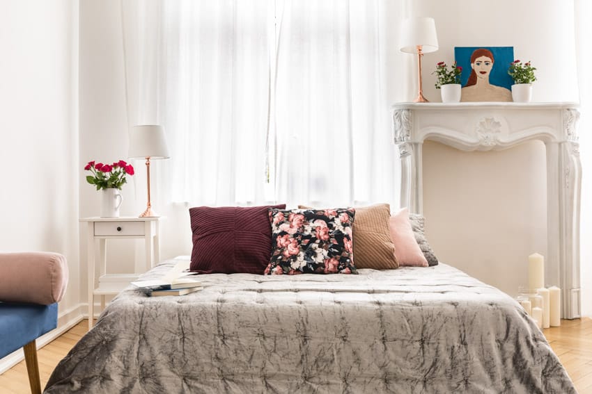 Bedroom with printed comforter, floral pillows and tall console table