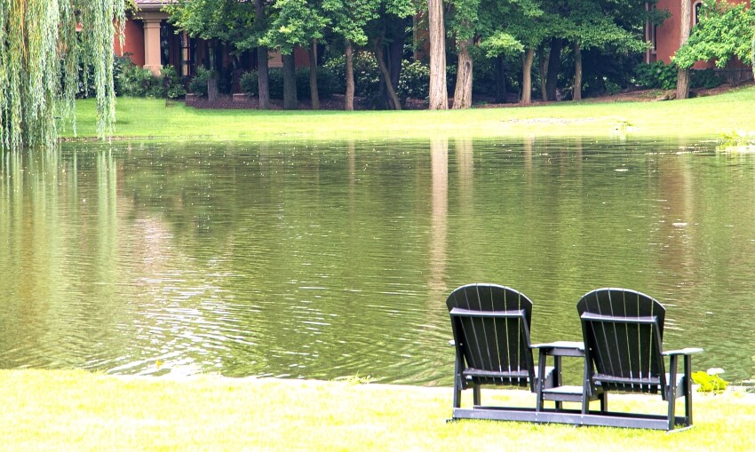 Black adirondack chairs overlooking a lake and trees