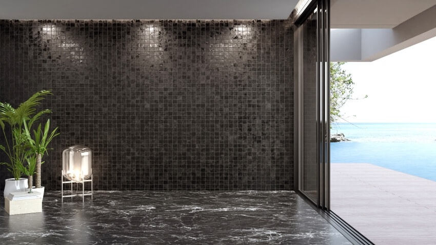 Blank dark tiles wall on empty black marble floor of large living room in modern house