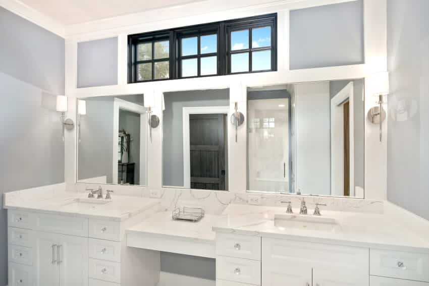 Bright bathroom with sconce lights, clerestory windows, and Carrara marble countertops
