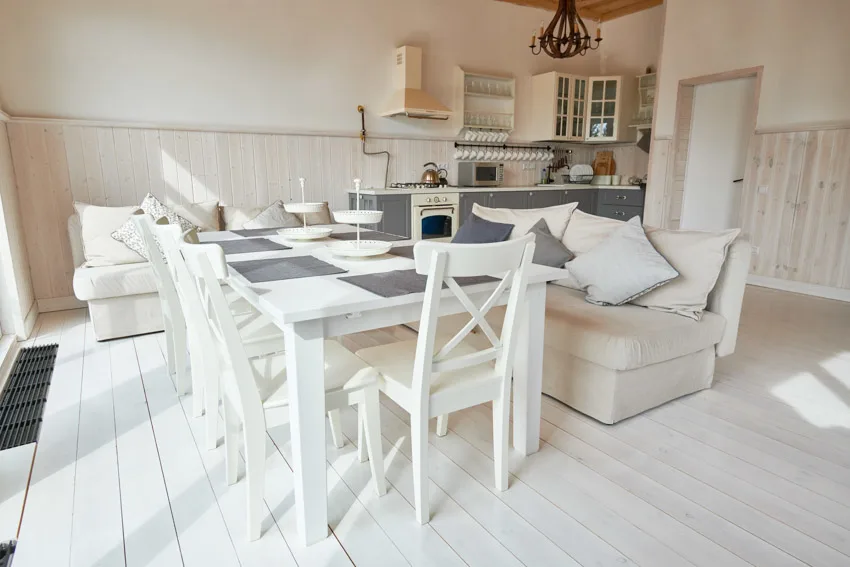 Room with white painted floors, wrought iron chandelier and beige range hood