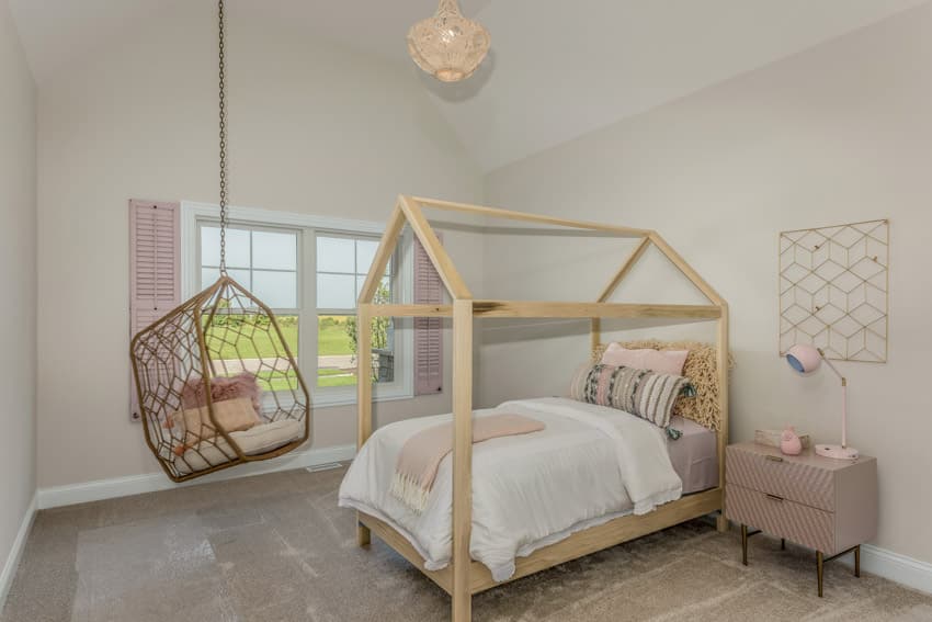 Children's room with four poster bed, white wall, nightstand, and egg chair