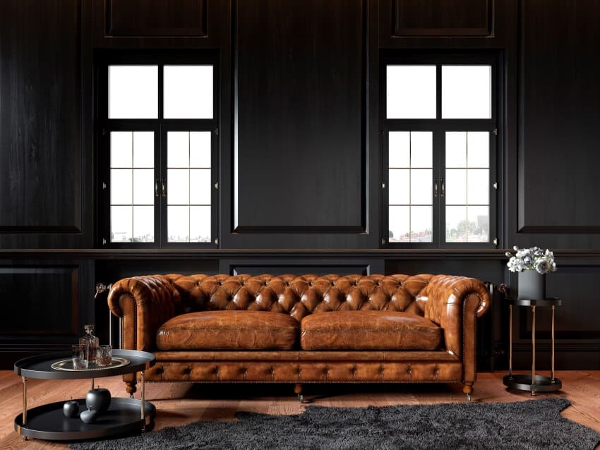 Classic loft black interior with black wood panel walls, and dark brown chesterfield couch